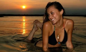 Девушка с красивой улыбкой в море на фоне заката